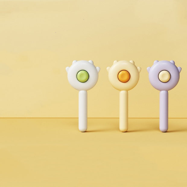 Three colorful baby rattles on a yellow background