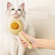 Cat being petted with a yellow handheld massage tool against a neutral background